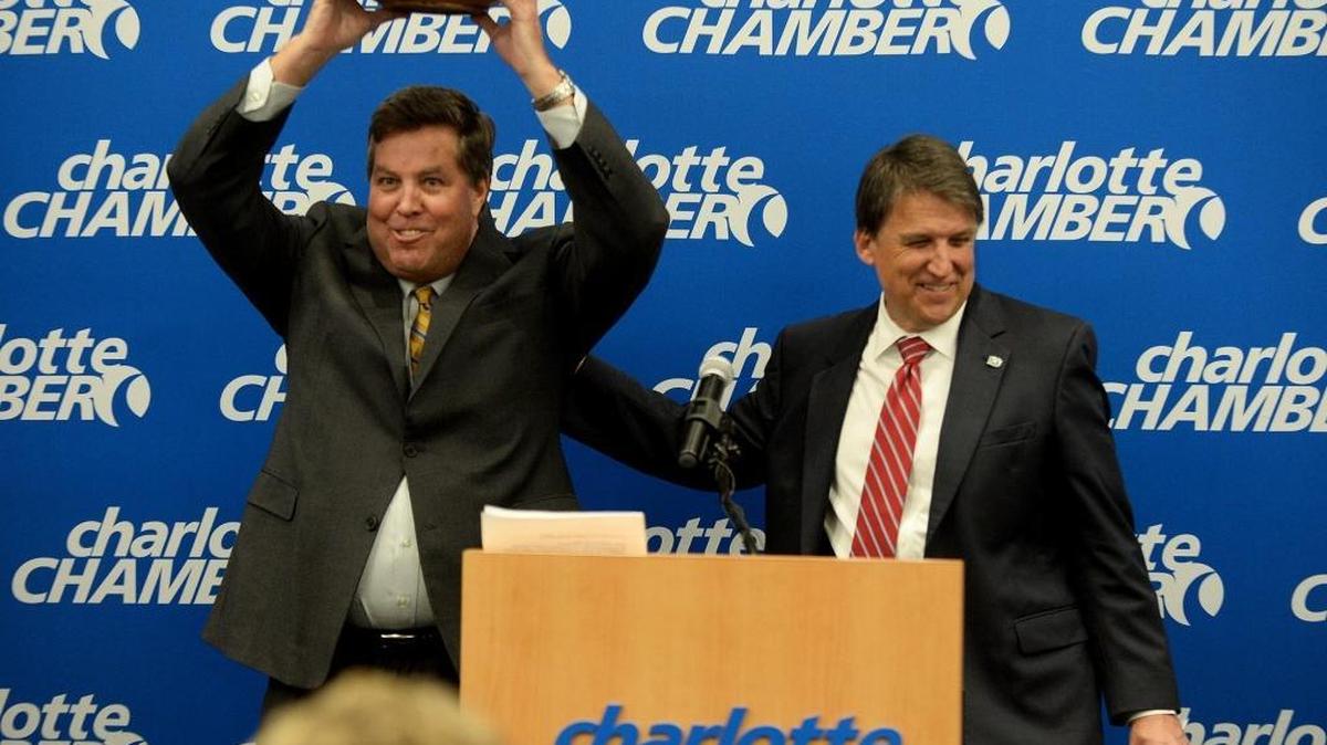 John McCabe, left, senior vice-president of Global Operations at PayPal, holds up a carved wooden bowl (made by an artist from a tree struck by lightning outside the state capitol), presented to him by Gov. Pat McCrory, right, after McCrory announced that PayPal, Inc. planned to open a Global Operations Center in Charlotte.