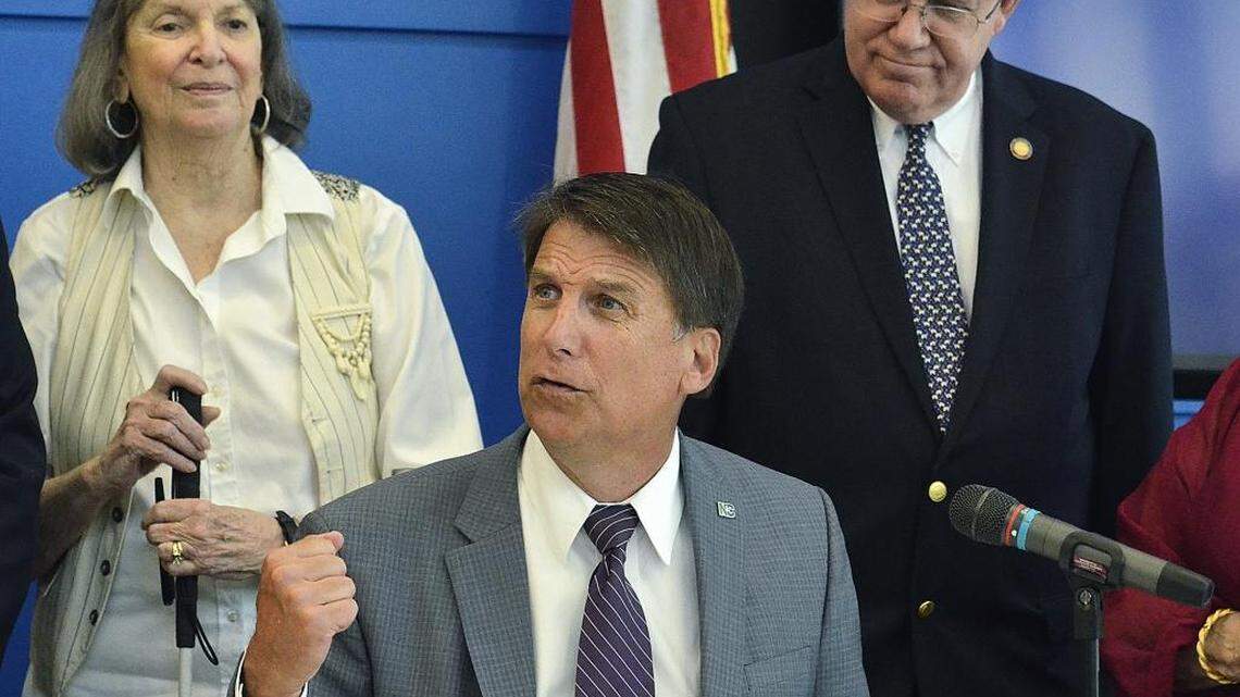 
Gov. Pat McCrory signs a ridesharing bill Friday morning at the recently renovated Charlotte Chamber. Special guests included Rita Reed (left) a sight impaired artist and Uber user, and Rep. William Brawley (right).
