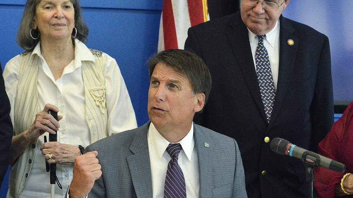 
Gov. Pat McCrory signs a ridesharing bill Friday morning at the recently renovated Charlotte Chamber. Special guests included Rita Reed (left) a sight impaired artist and Uber user, and Rep. William Brawley (right).
