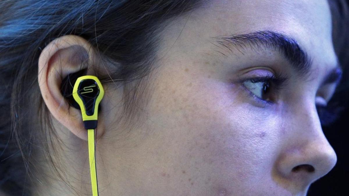 A model wears SMS Audio BioSport In-Ear Headphones at the Intel booth during the International CES in Las Vegas. Spotify says a “significant” number of its 30 million paying subscribers are charged $3 more per month because they sign up through Apple, which takes a cut of up to 30 percent.