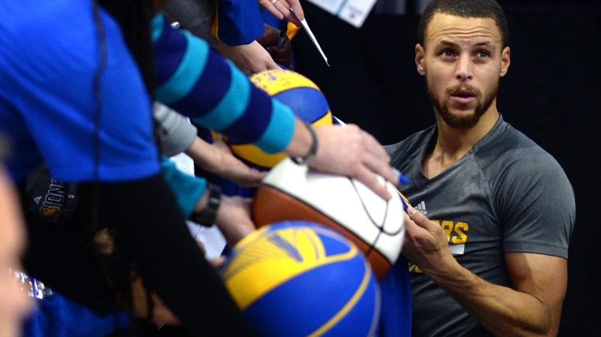 Golden State Warriors guard Steph Curry, right, stops to sign autographs for fans prior to action against the Charlotte Hornets at the Spectrum Center in Charlotte on Jan. 25.