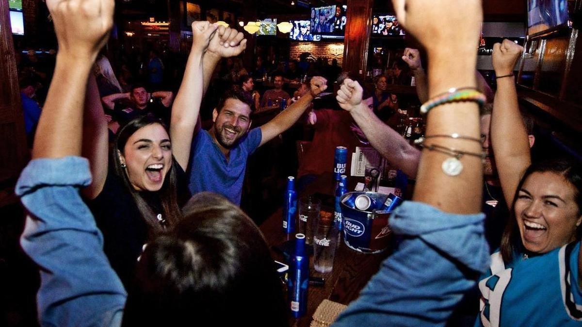 Crowds cheer a Panthers score as they watch the action in a crowded All-American Pub in the Bland Street/South End area during Thursday’s Panthers pre-season game against the Pittsburgh Steelers. Left to right in back are Stephanie Pedro, Justin Stancato, Cam Blankenship, and Natalie Scuzzarella, and in front middle with back to camera is Jenna Muscarello.