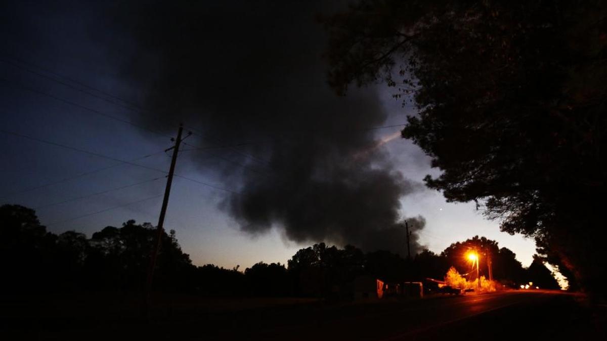 Light from a light pole shows a house near a plume of smoke from a Colonial Pipeline explosion, Monday, Oct. 31, 2016, in Helena, Ala. Colonial Pipeline said in a statement that it has shut down its main pipeline in Alabama after the explosion in a rural part of the state outside Birmingham.