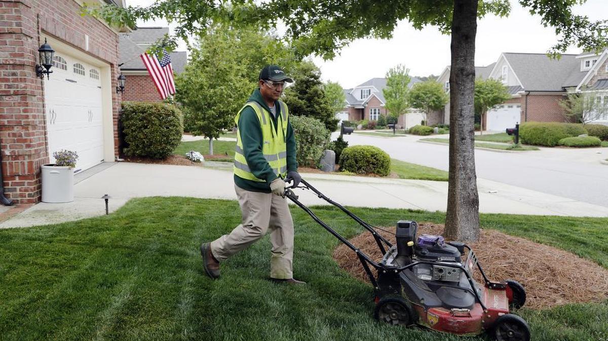 Ruben Lugo from Mexico mows grass on the grounds of the DeVintage subdivision in Cary in this photo from April. Lugo is here on an H-2B visa to work for Greenscape Inc., a Raleigh landscaping company.