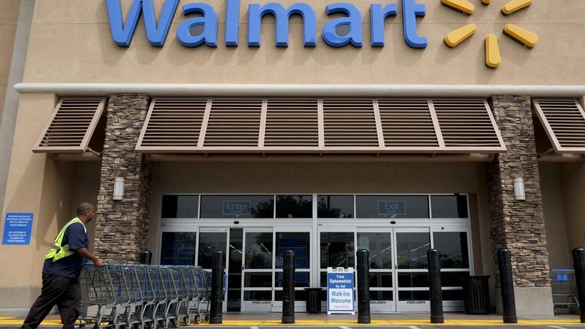 FILE - In this May 9, 2013, file photo, a worker pushes shopping carts in front of a Wal-Mart store in La Habra, Calif. Wal-Mart is replacing a program that offered free shipping but had an annual fee with one that has a lower free shipping threshold and faster delivery as it hopes to answer Amazon's powerful Prime membership success.