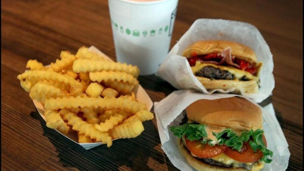 A “Smoke Shack” (top) and a “Shack Burger” along with fries and a strawberry shake at this Shake Shack spot in Coral Gables, Fla.