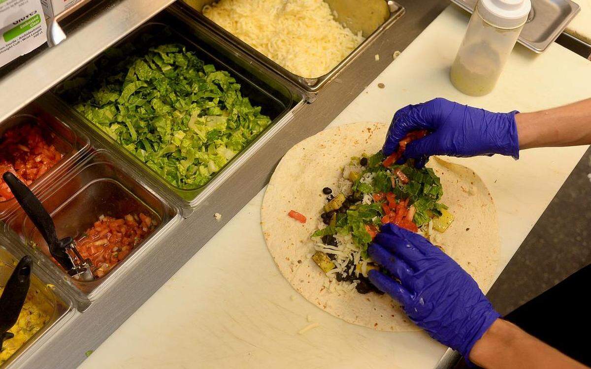 Employee Garrett Little puts tomatoes on a burrito during lunch at Phat Burrito restaurant in South End.
