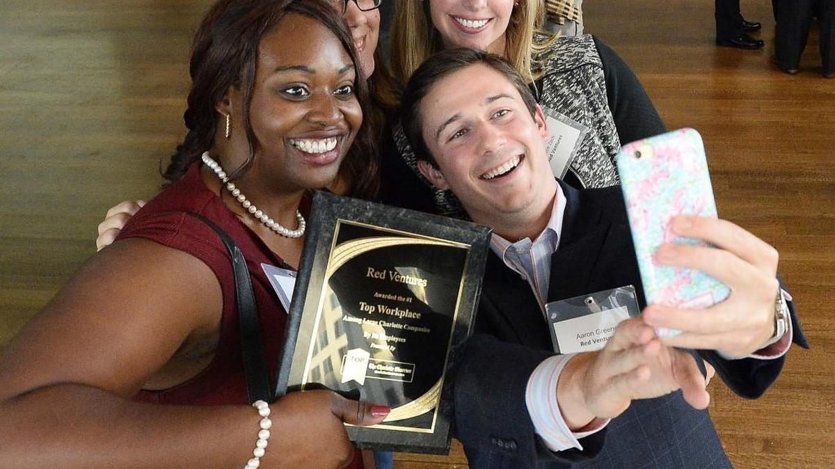 Employees with Red Ventures (from left) Lakisha Williams, Kelly McMurtrie, Katie Zach and Aaron Greene show their excitement by taking a selfie after receiving the award for first place in the large-company division during the Top Workplaces reveal event held at the Mint Museum on Sept. 23, 2015.