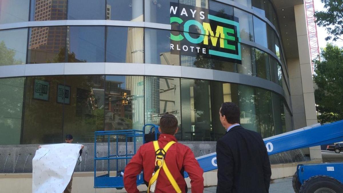 An “Always Welcome” sign being applied to the Westin Hotel in uptown Charlotte