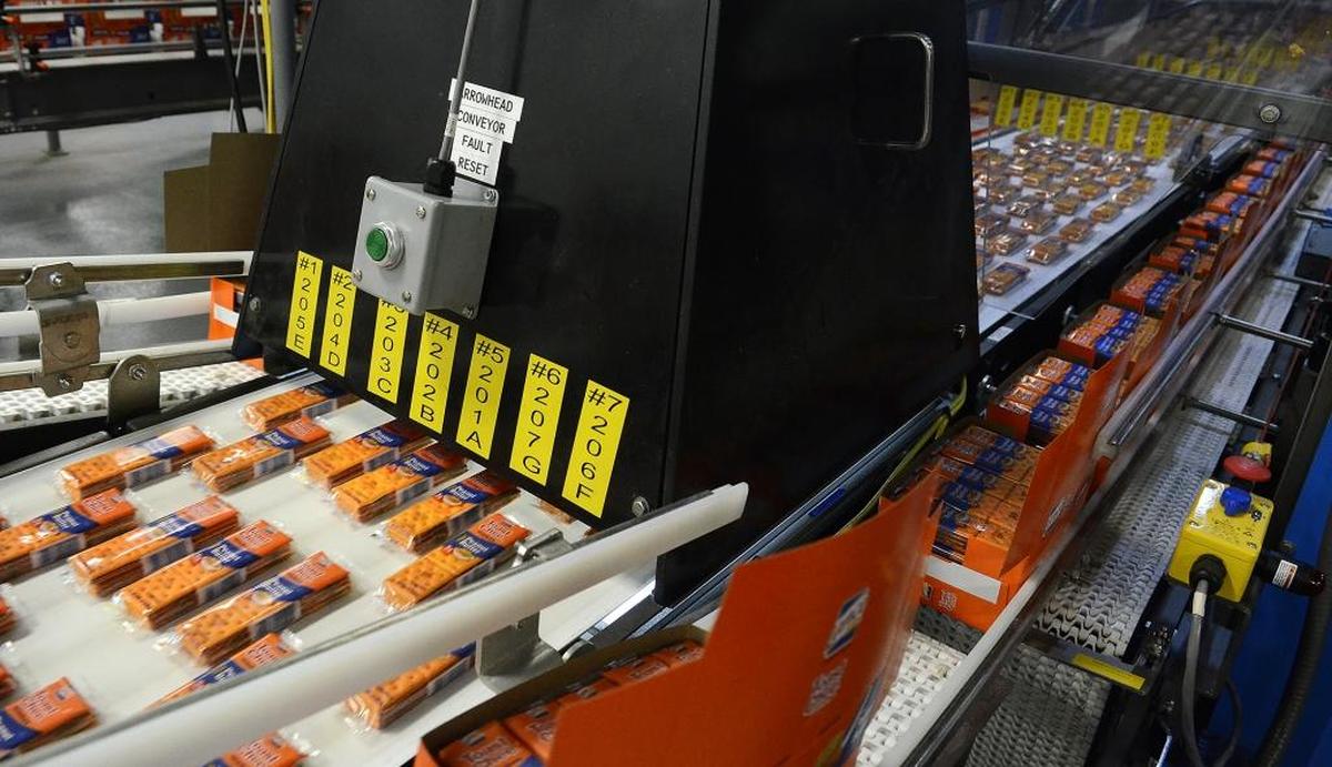 Packages of Toast Chee go beneath a laser scanning device as they head into a robotic packaging system where they are placed in cartons before being packed into cases for shipping.
