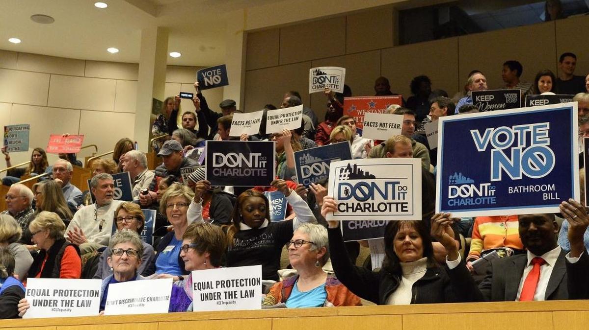 Members of the audience hold up signs before the start of the Charlotte City Council meeting’s vote on the nondiscrimination ordinance on Feb. 22.