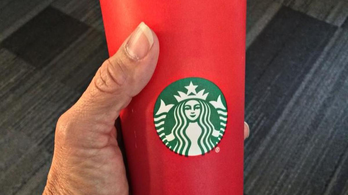This November 9 photo shows a consumer holding the 2015 Starbucks holiday cup in Washington, D.C. The unadorned red cup has come under fire for its lack of design. Creating a culture of belonging, inclusion and diversity is one of the core values of Starbucks, the company said.