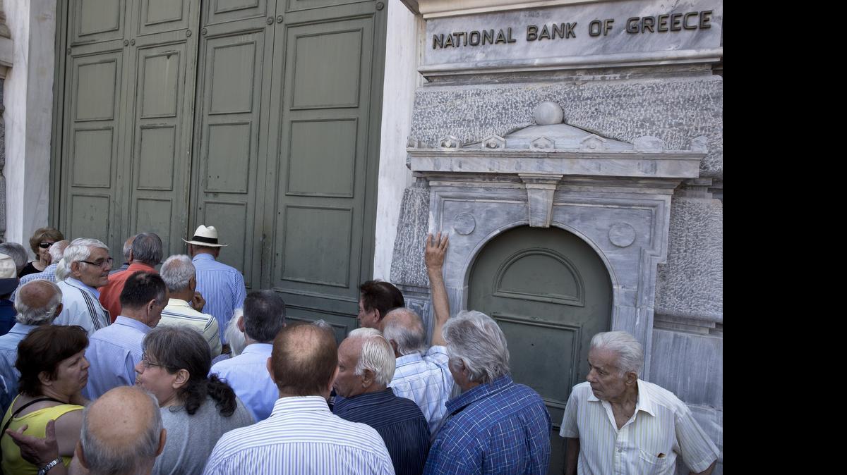 
 FILE - In this file photo dated Monday, June 29, 2015, elderly people wait to receive their pensions outside the National Bank of Greece headquarters in Athens, as anxious Greek pensioners swarmed bank branches and lined up at ATMs. Following the referendum call by Prime Minister Alexis Tsipras and the ensuing decision by Greece’s euro partners not to extend Greece’s bailout beyond the end-June deadline, the Greek government announced a series of capital controls to prevent a bank run. The most onerous of the controls was a decision to cap daily withdrawals from ATMs at 60 euros. (AP Photo/Petros Giannakouris, FILE)
