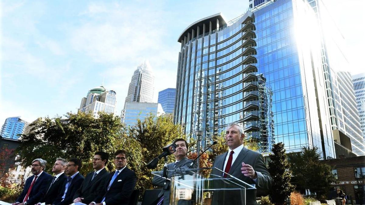 In November, the CEO of asset-management firm Barings, Tom Finke, right, speaks at a ceremony at Romare Bearden Park to dedicate 300 South Tryon, (visible in background), a new office tower that Barings is anchoring.