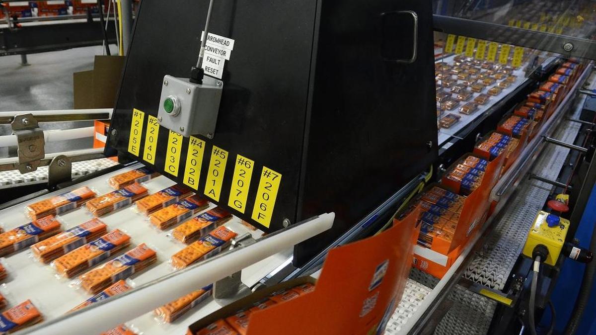 Packages of Toast Chee travel under a laser scanning device as they head into a robotic packaging system during a March 2015 tour of the Snyder’s-Lance plant in Charlotte. The snack maker confirmed Tuesday that it has laid off 24 people in its accounting department.
