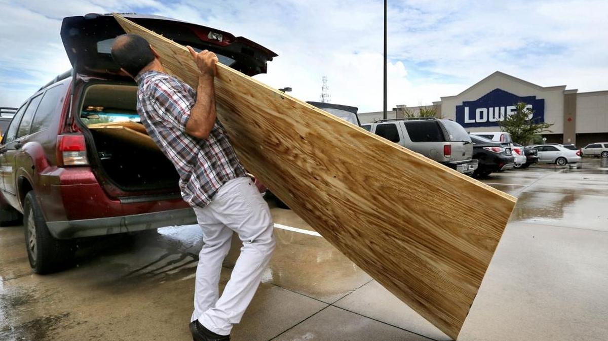 Home owner Hemant Panchal of Sanford, Fla., wrestles plywood into his vehicle at a Lowe’s store in Casselberry, Fla., north of Orlando, as central Floridians make last-minute preparations for the strike of Hurricane Matthew on Thursday.