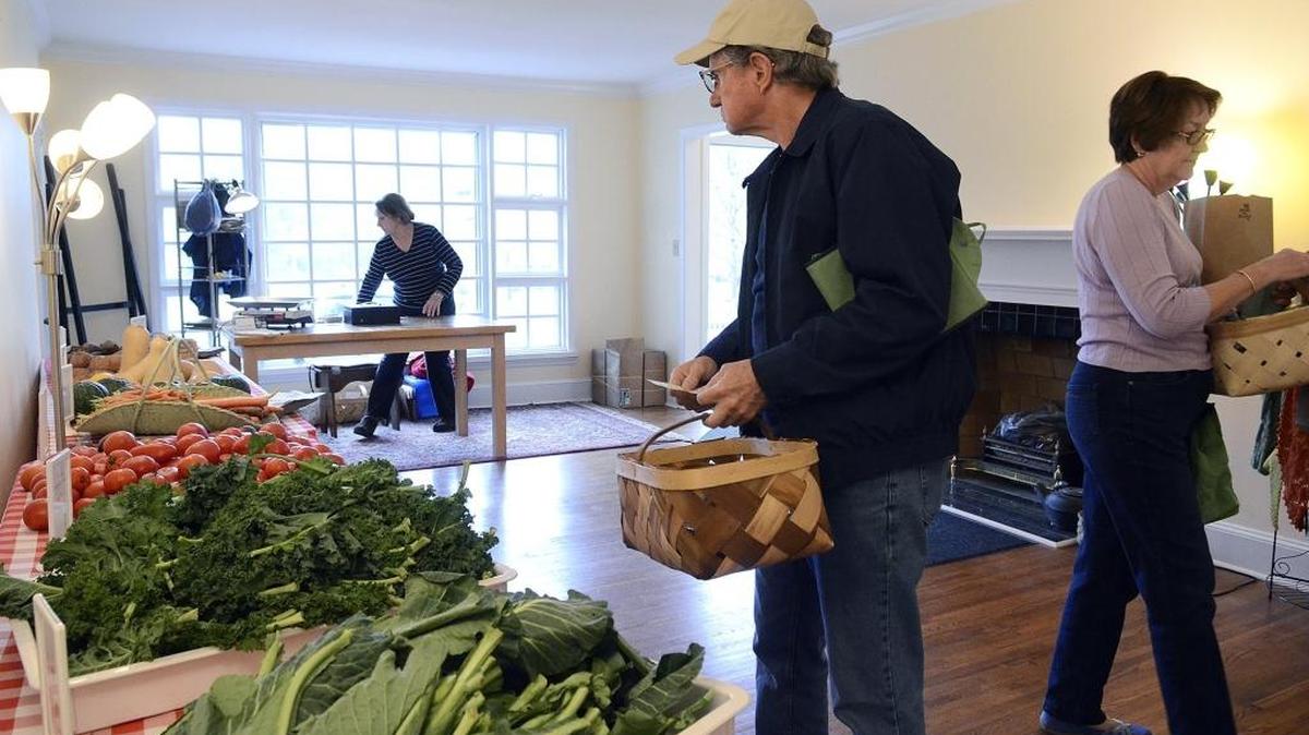 Shoppers Walter Gilewski (center) and Sue Rykens (right) check out the produce at the Newell Farmer's Market.