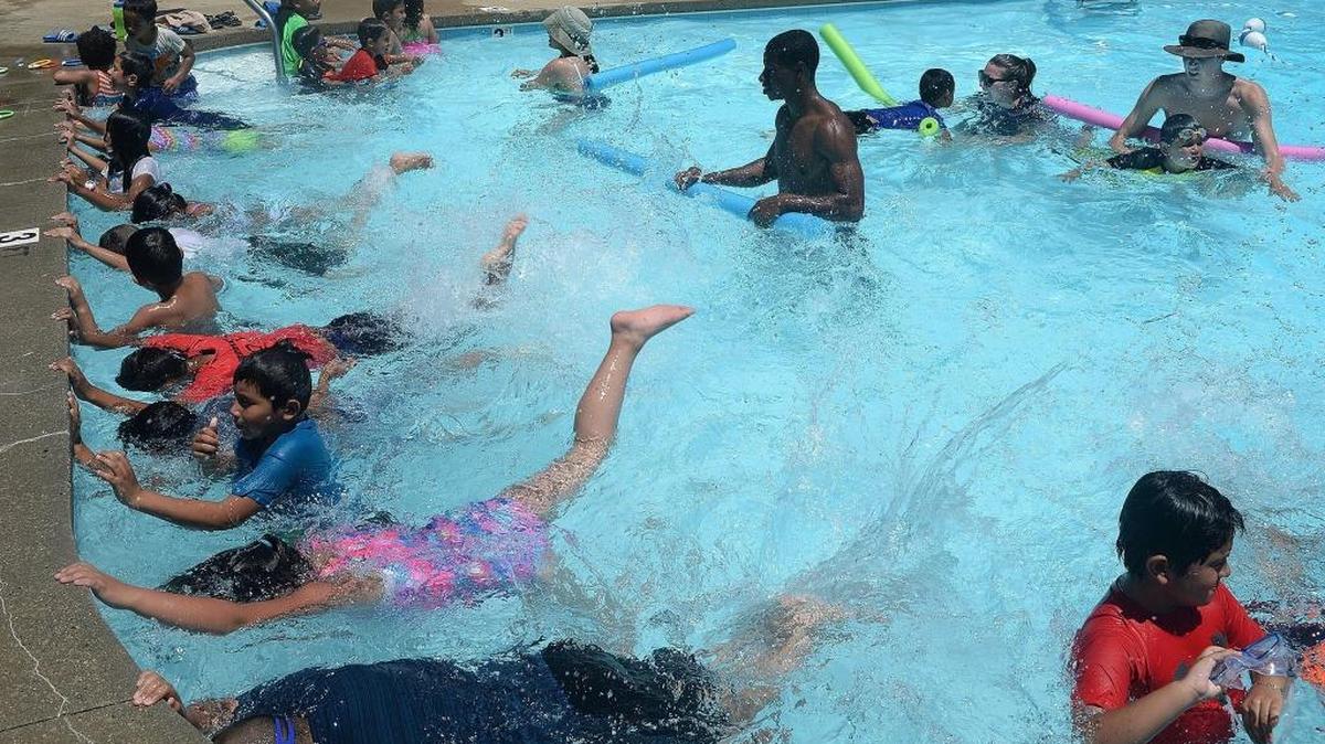 Instructors help children learn to float and swim during an expanded water safety program at The Highlands apartments on Archdale Drive. The program was launched by the YMCA to keep immigrant and minority kids from drowning in pools at apartment communities in the city. Most of those pools do not have lifeguards.