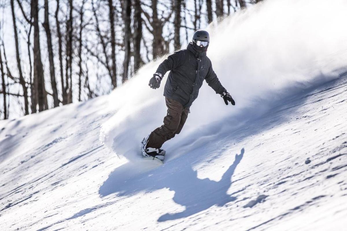 A snowboarder making turns on Upper Flying Mile run at Sugar Mountain ski resort near Banner Elk.