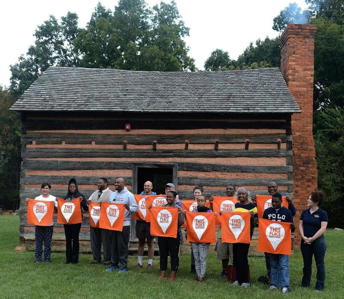A Charlotte area group participating in the Slave Dwelling Project holds up flags Saturday morning reading “This Place Matters” – referring to the Pineville cabin where they spent the night. The building at the President James K. Polk Historic Site was reconstructed in the 1960s using materials dating to the early 19th century. Polk’s family owned slaves.