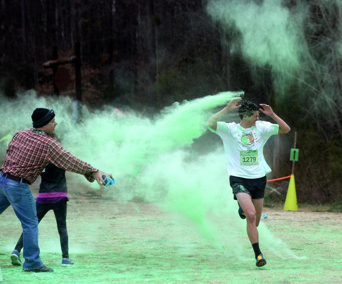 Nick Kilbarger, the winner of the 2017 Color Me Green 5K Trail Run, is hit with green dye as he finishes the race.