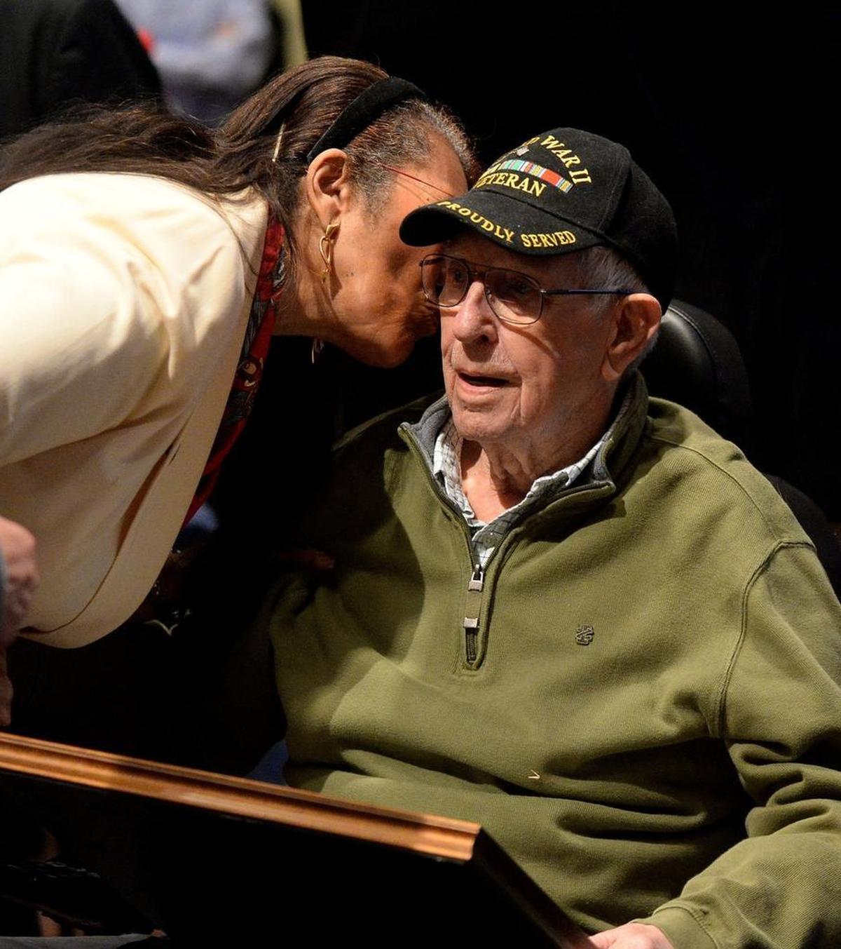 School board member Thelma Byers-Bailey kisses Ralph Lee England as the board parades by his wheelchair to thank him for his service in World War II.