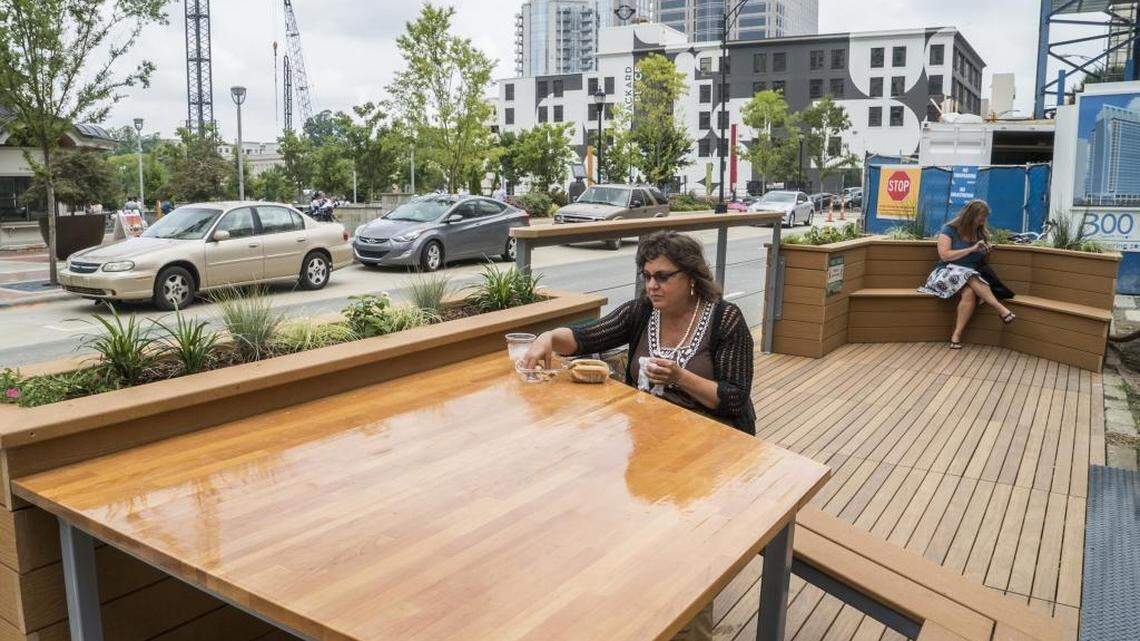 
Heather Gallant took time from her job at Duke Energy to have lunch at the parklet adjacent to Valhalla in Brevard Court on Friday. Two parklets have been installed on roadway blocked by construction at Brevard Place on South Church Street across from Romare Bearden Park.

