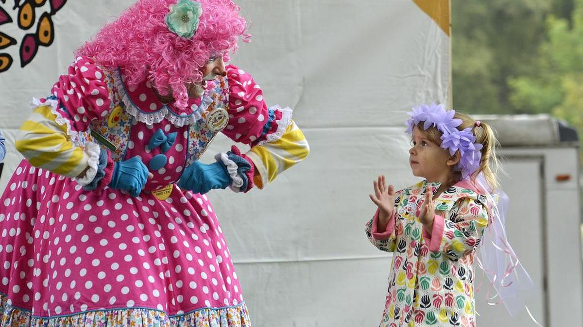 Itsy Bitsy the clown shows 2-year-old Alyssa Hollingsworth how to do the “Chicken Dance” at the 2015 Festival in the Park.