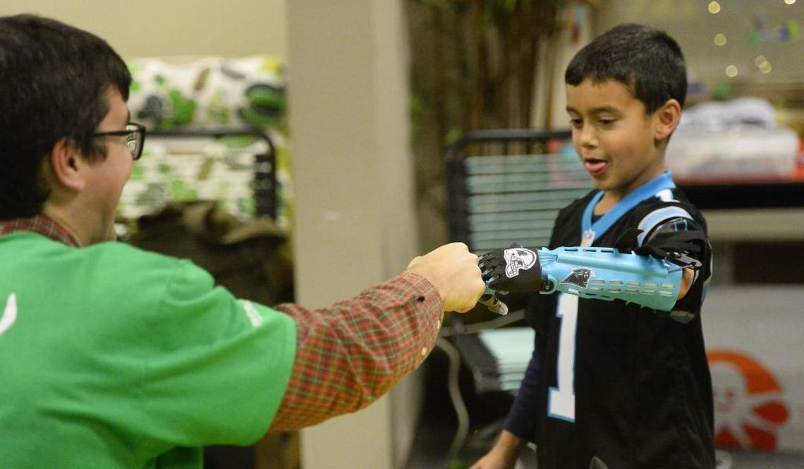 Joel Payne, 7, fist-bumps Helping Hand Project founder Jeff Powell, founder of The Helping Hand Project, after receiving his new 3D-printed arm last week.