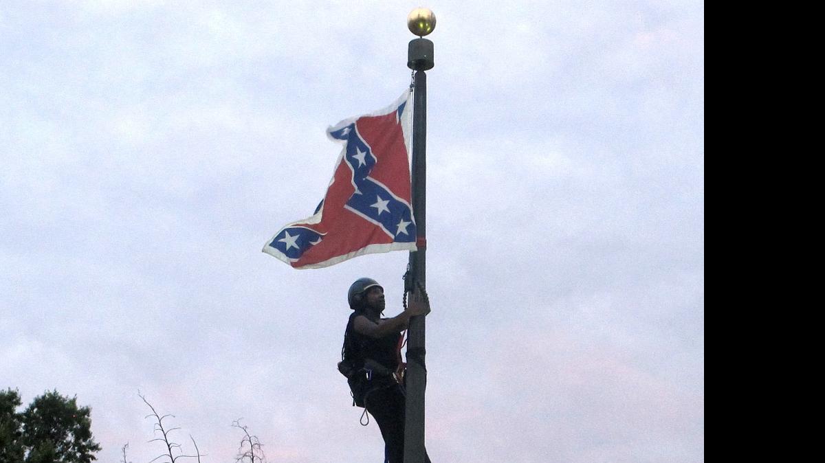 
Bree Newsome of Charlotte, N.C., climbs a flagpole to remove the Confederate battle flag at a Confederate monument in front of the Statehouse in Columbia, S.C., on Saturday, June, 27, 2015. She was taken into custody when she came down. The flag was raised again by capitol workers about 45 minutes later. 

