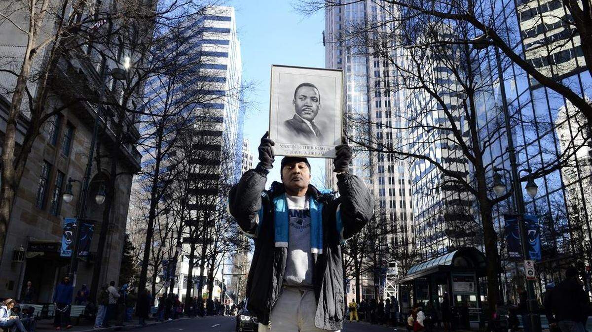 Paris Huntley, Jr., carries a portrait of Martin Luther King, Jr., in the 2016 MLK parade in Charlotte. This year, the city won’t hold a parade due to COVID-19.