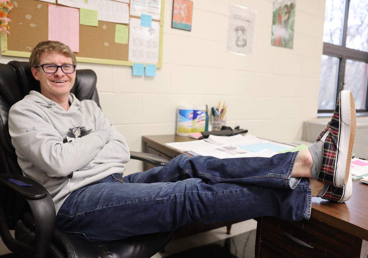 Jeff Swicegood, a teacher at Providence High School, props his feet on his desk Friday after school. Students in his class gifted him the shoes he is wearing.