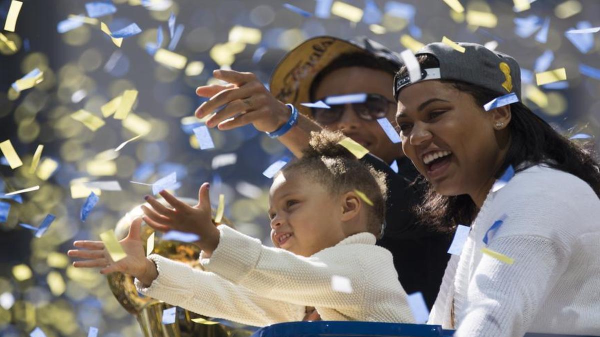 
Stephen Curry, daughter Riley Curry (L) and wife Ayesha Curry (R) celebrate as confetti falls during the Golden State Warriors Victory Parade in Oakland, California. 
