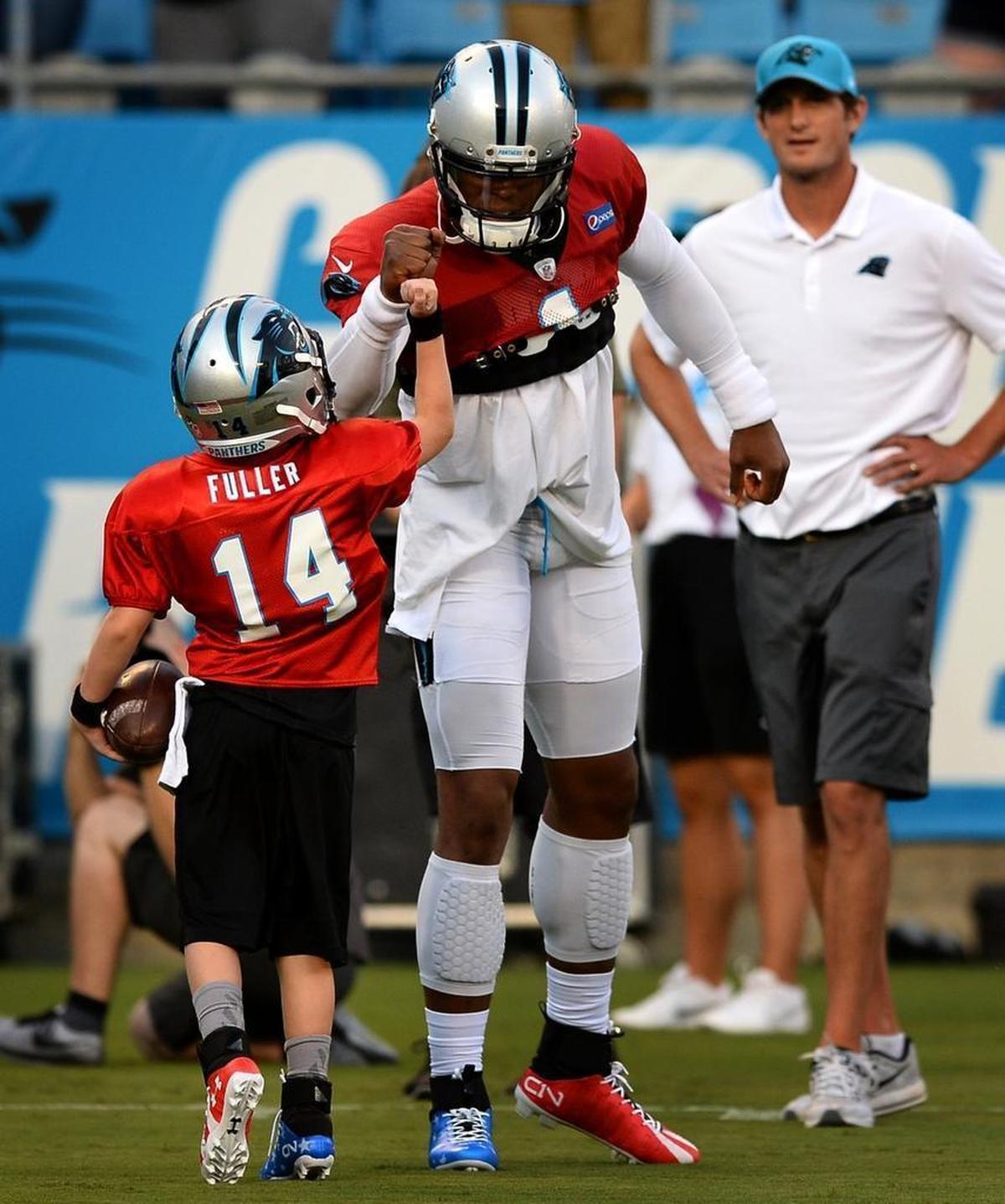 Carolina Panthers quarterback Cam Newton, center, bumps fists with Domanic "Dom" Fuller, 8, back to camera, during Friday’s Fan Fest at Bank of America Stadium.