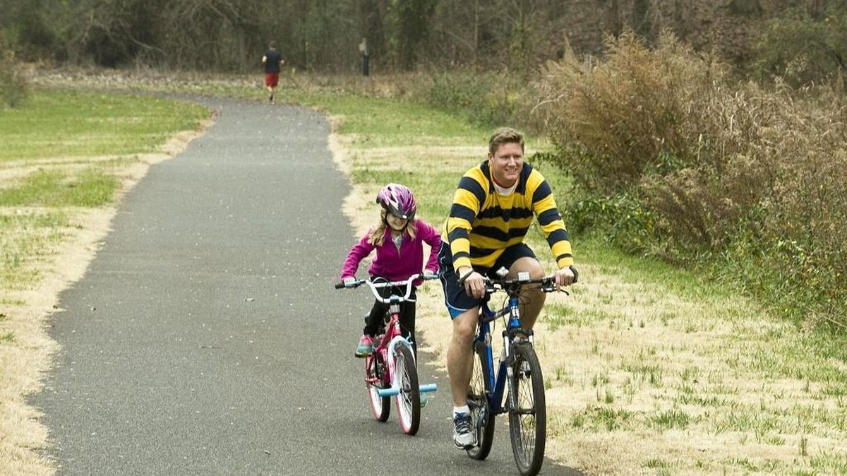 Mark Becker, right, leads his daughter, Mila along a greenway in Davidson.