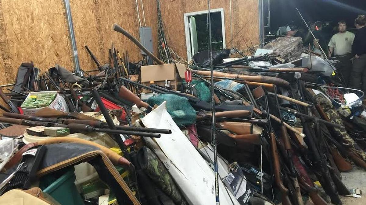 Rifles, tools and fishing gear stacked in storage building.