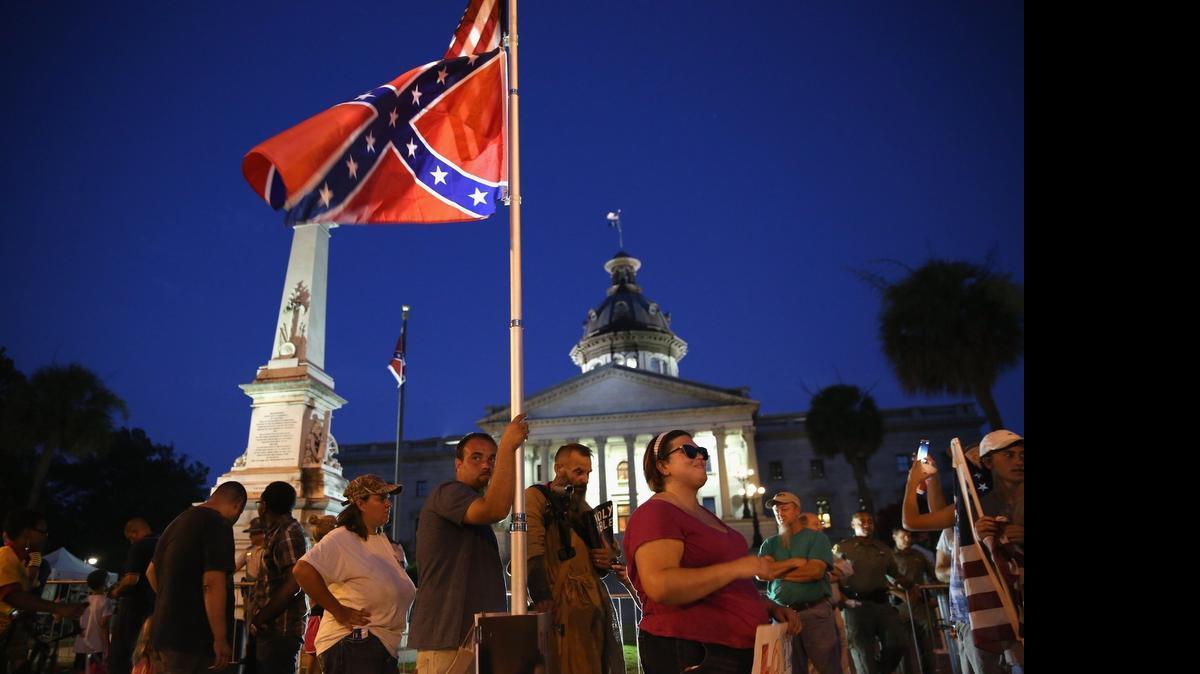 
COLUMBIA, SC - JULY 09: Confederate flag supporters stand outside the as "Stars and Bars" flies in front of the South Carolina statehouse on its last evening on July 9, 2015 in Columbia, South Carolina. South Carolina Governor Nikki Haley signed a bill to remove the Confederate flag from the statehouse grounds Friday morning. 

