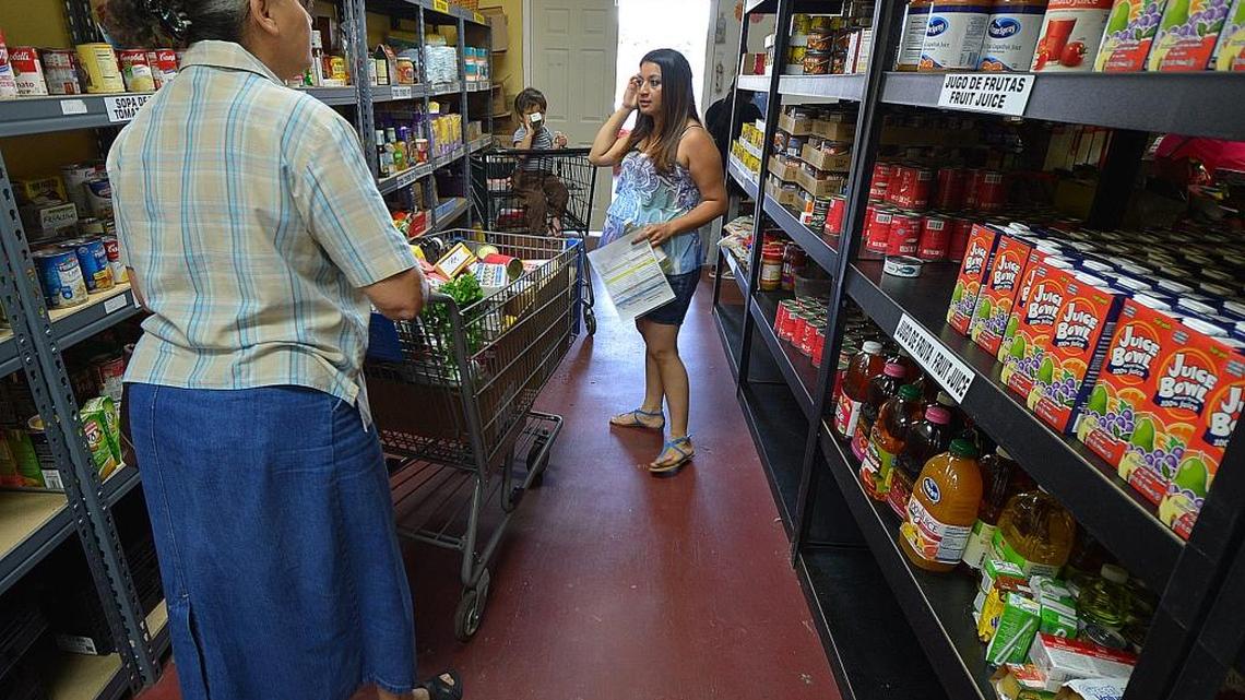 Volunteer Veronica Munoz, right, help a client with picking out items she might need at the Camino Community Center pantry. The Camino Community Center is an organization that serves low income people in the Greater Charlotte area by providing services to help them meet some basic needs during a crisis