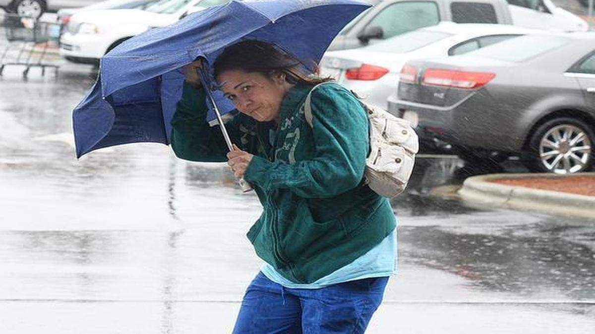 
A customer shields herself from the rain and wind using an umbrella at the Quail Corners Harris Teeter on March 5. The National Weather Service has forecast temperatures in the 70s for Wednesday but also the chance of thunderstorms this week.
