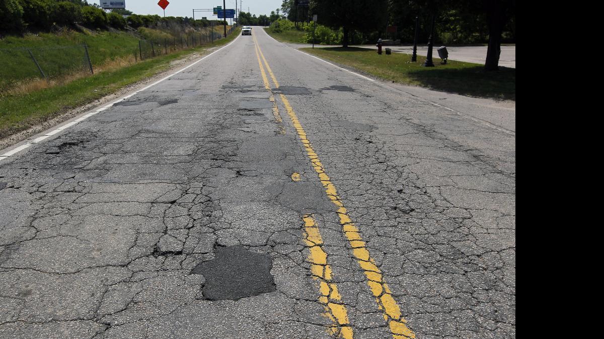 
Vehicles maneuver through patches, cracks and potholes on Yonkers Road in Raleigh. Rep. John Torbett backed away from a plan to raise funds for repaving roads throughout the state in part by adding a new 6.5 percent tax to the annual price of automobile insurance. 
