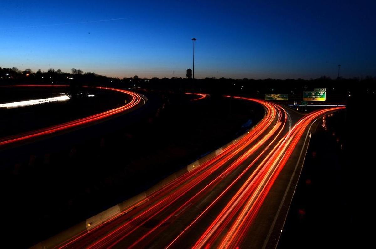 Motorists tail lights stream by on the Brookshire Freeway with non-working highway lights. This photograph is shot from an overpass on Hamilton St. Directions for Beatties Ford Road and Statesville can be seen on the overhead signs at right.