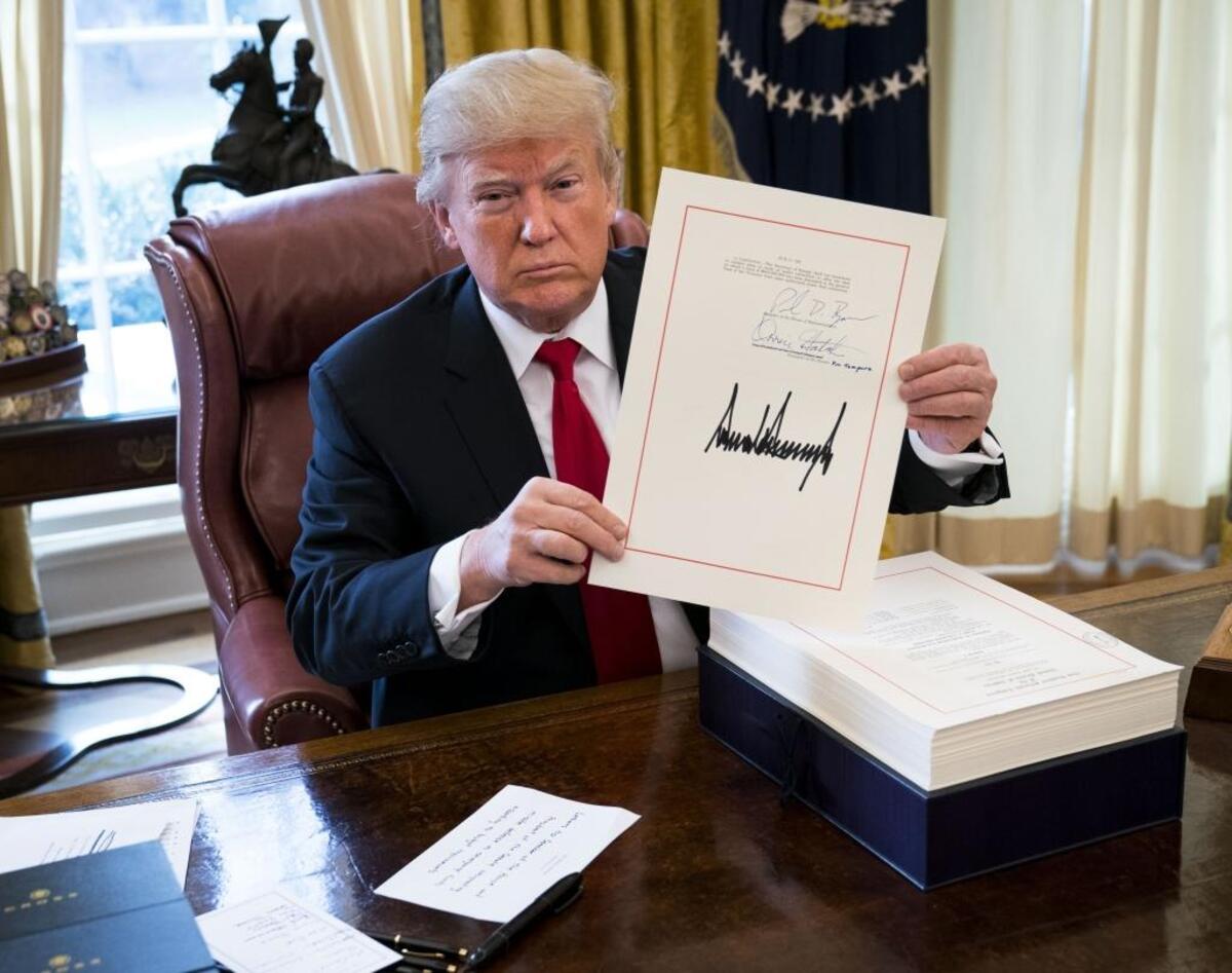 President Donald Trump displays his signature on a sweeping tax bill in the Oval Office of the White House, in Washington, Dec. 22, 2017. Trump signed the bill on Friday that Republicans promise will benefit the middle class, despite warnings from Democrats that the new law could be harmful to the country.