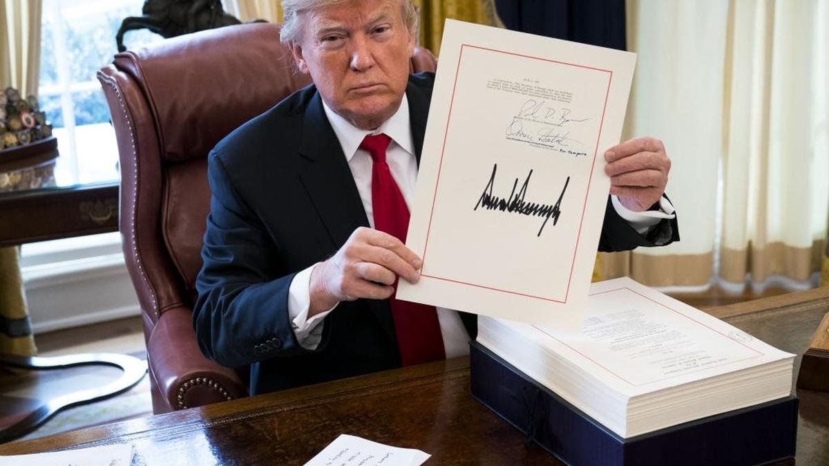 President Donald Trump displays his signature on a sweeping tax bill in the Oval Office of the White House, in Washington, Dec. 22, 2017. Trump signed the bill on Friday that Republicans promise will benefit the middle class, despite warnings from Democrats that the new law could be harmful to the country.