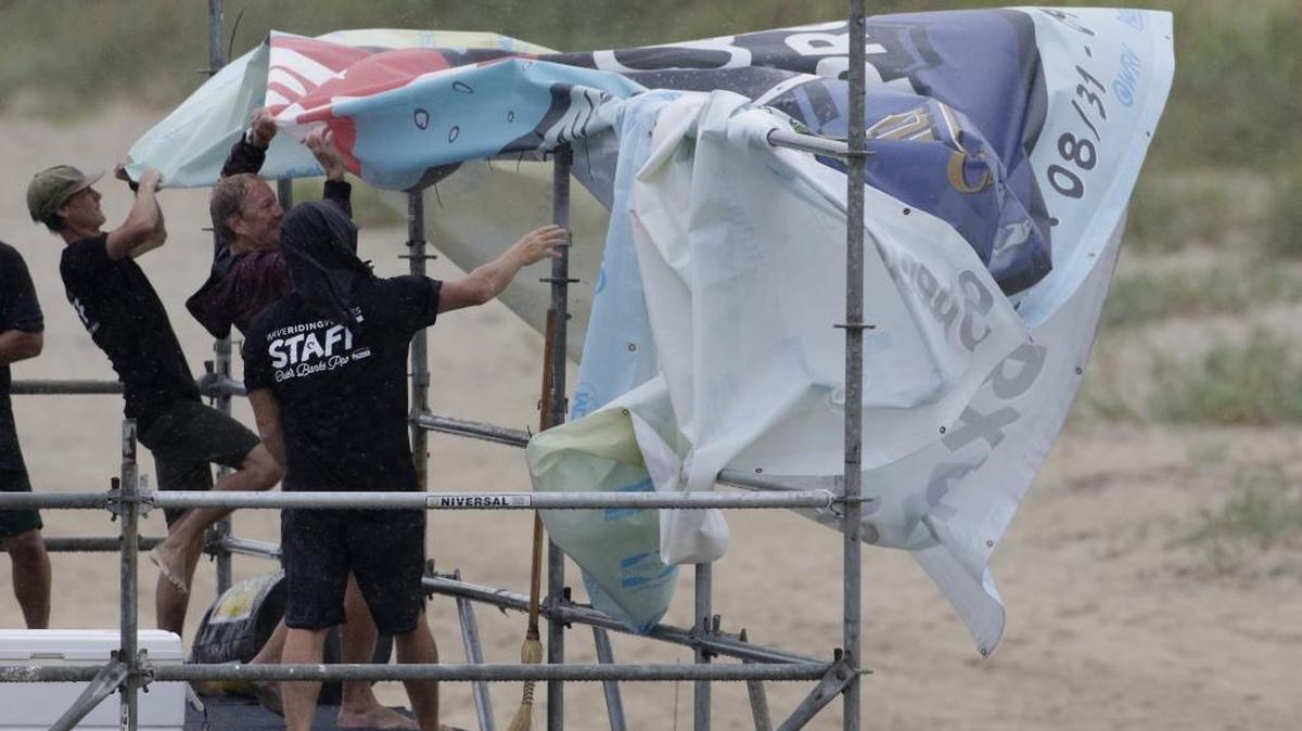 Staff members for the MRV Outer Banks Pro surf tournament take down a banner in Nags Head, N.C., Friday, Sept. 2, 2016, as Hermine heads toward the Outer Banks. (AP Photo/Tom Copeland)