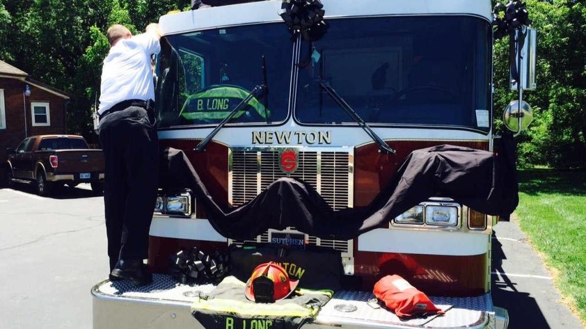 Black ribbons and bows being placed on a Newton firetruck.