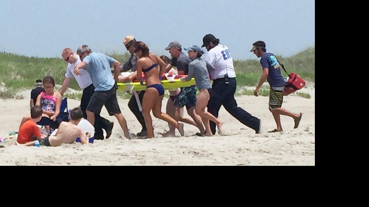 
People surround and attend to a 68-year-old man that was bit by a shark in waist-deep water off Ocracoke Island, N.C., Wednesday, July 1, 2015. The man suffered wounds to his ribcage, lower leg, hip and both hands as he tried to fight off the shark.
