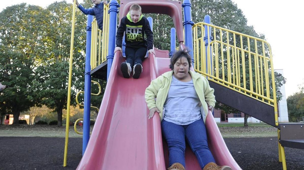 Jessica Poole, 21, right, and Justin Poole, 12, fly down a slide at Winthrop Park in Rock Hill, while J.T. Poole plays near a pole. Winthrop Park will transform into Miracle Park, an athletic and play park for people with disabilities and special needs.