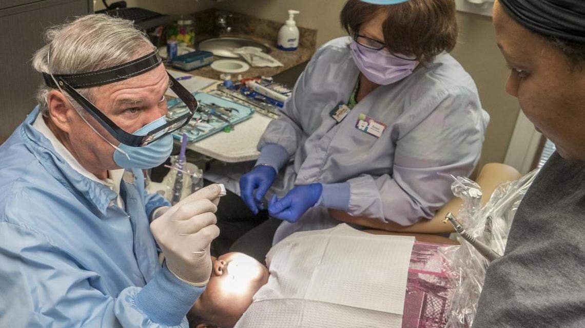 
Dr. Cordell Scott of Lincoln Dental Services talks with Letisha Young, mother of patient Angalecia Morrison, 9, about a dental procedure. At center is dental assistant Renee Lee. 
