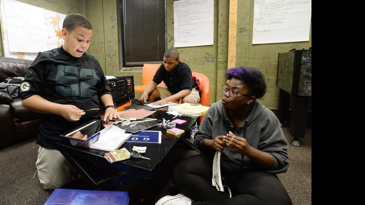 
From left, Christoper Matthews 12, production manager; Andrew Givens 12, logistics coordinator; and Shaquetta Gathers 15, CEO; build LED solar lanterns  at the Salvation Army Boys and Girls Club on Belmont Ave. in Charlotte.

