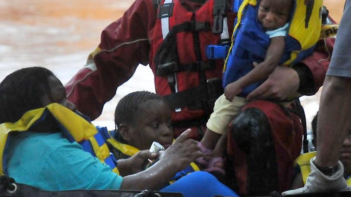 Jason Dickson of the Charlotte Fire Department swift water rescue team carries a 1-year-old child as residents are evacuated from apartments on Southwest Boulevard on Aug. 5, 2011.